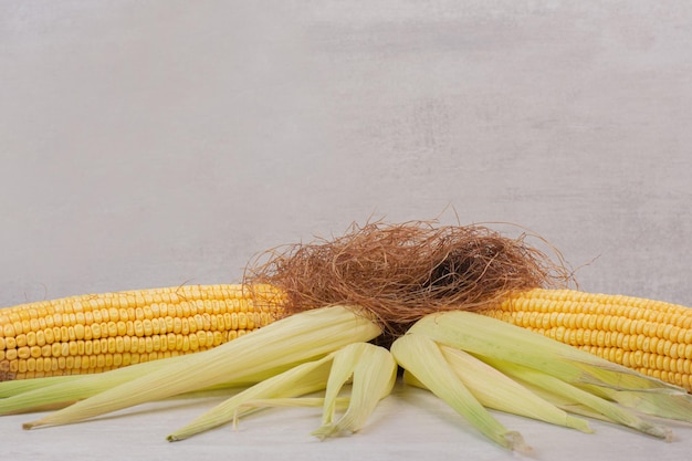 Free photo fresh corns on cobs on white table.