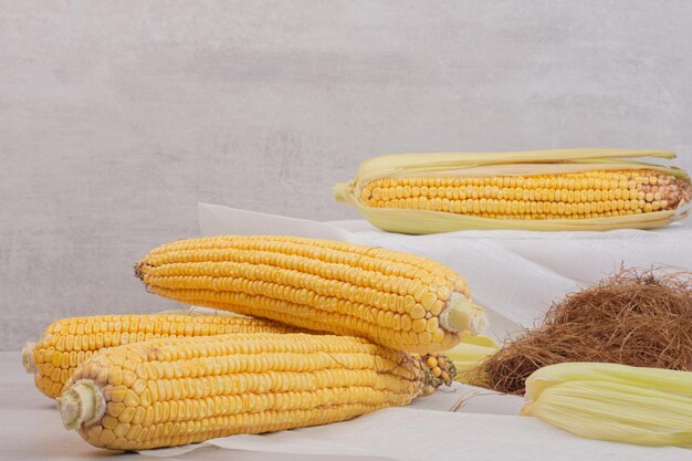 Fresh corns on cobs on white table.