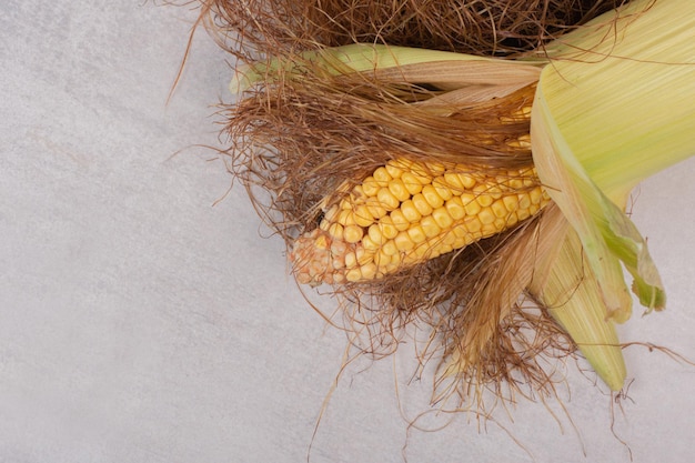 Fresh corns on cobs on white table.