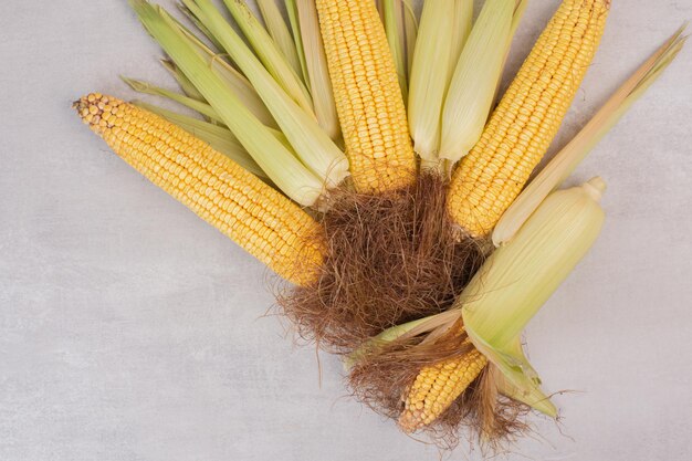 Fresh corns on cobs on white table.