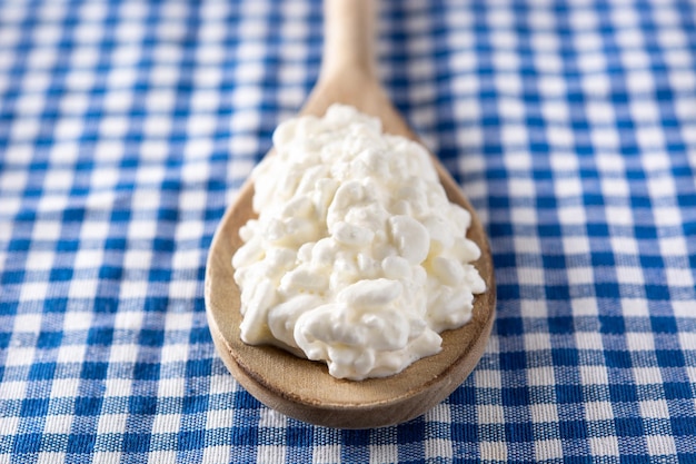 Fresh cottage cheese on blue tablecloth background