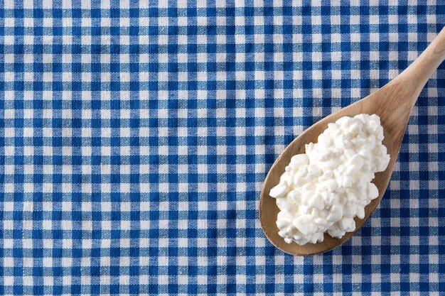 Fresh cottage cheese on blue tablecloth background