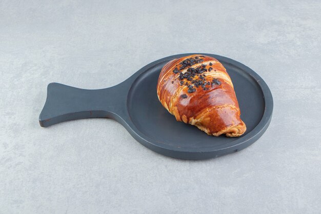 Fresh croissant decorated with drop chocolate on black board. 