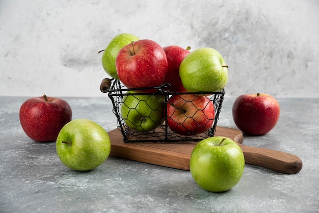 Свежие вкусные зеленые и красные яблоки в металлической корзине.