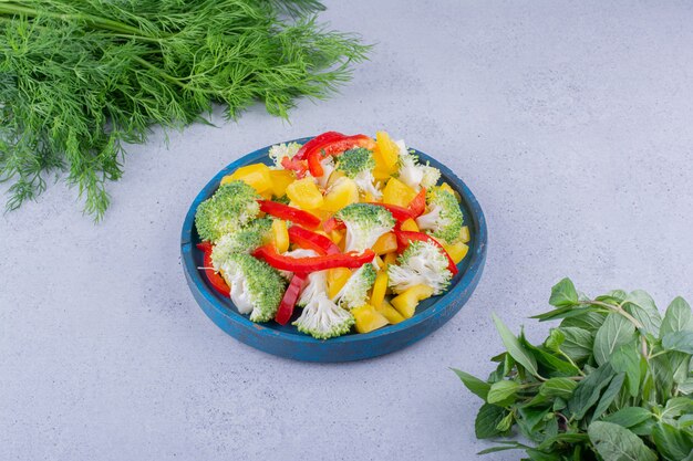 Fresh dill and mint bundles next to a salad platter on marble background. High quality photo