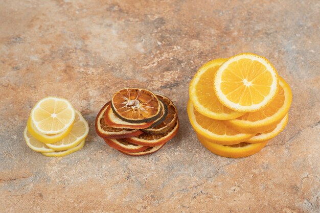 Fresh and dried lemon slices on marble surface.