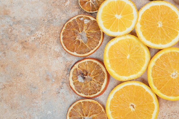 Fresh and dried orange slices on marble background.