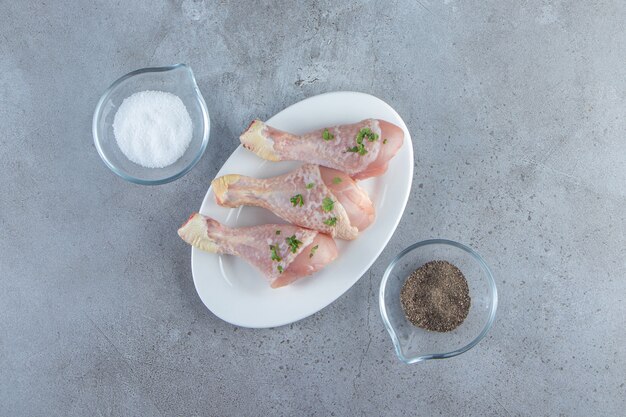 Fresh drumsticks on a plate, on the marble surface.