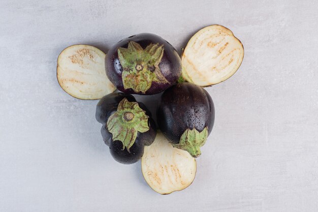 Fresh eggplants with water drops on stone surface. High quality photo