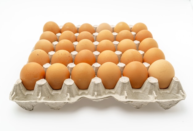 Свежие яйца в упаковке на белом фоне.