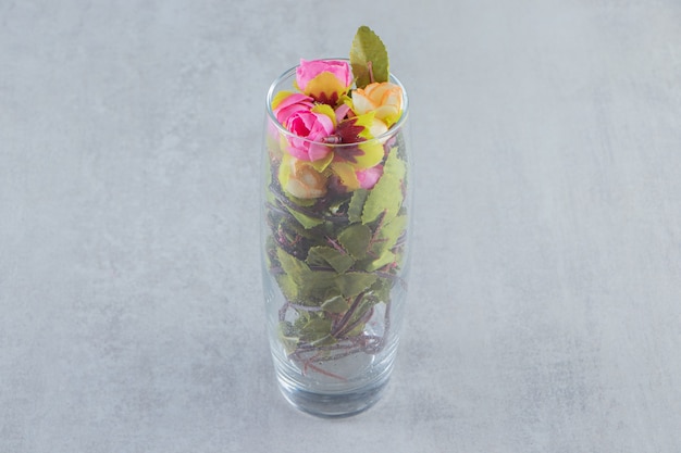 Fresh elegant flowers in a glass, on the white table.