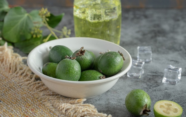 Feijoa fresca e bicchiere di limonata su sfondo di marmo