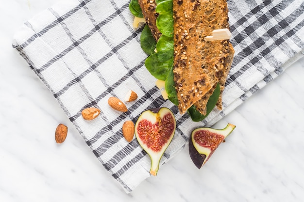 Fresh fig fruit slices and almonds near hot dog over napkin on kitchen counter