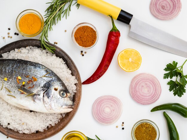 Fresh fish surrounded by knife and vegetables