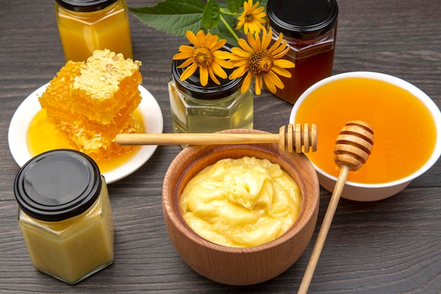 다양한 종류의 신선한 꽃 꿀과 나무 배경에 숟가락이 있는 벌집. 유기농 비타민 건강식품