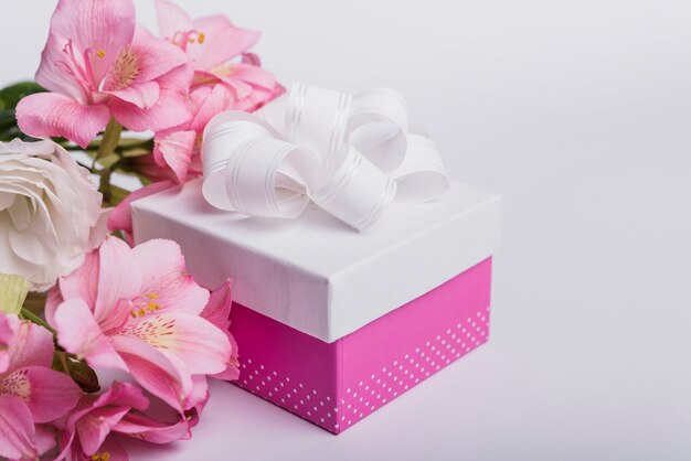 Fresh flowers and present box on white background