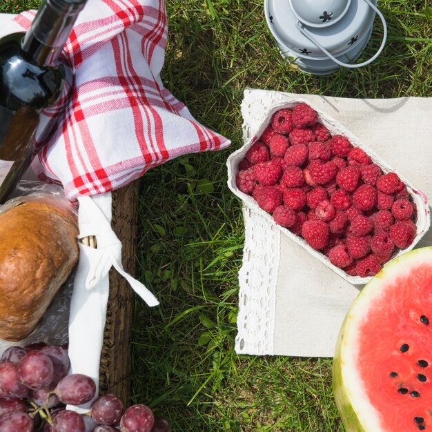 Fresh fruits and picnic basket on green grass