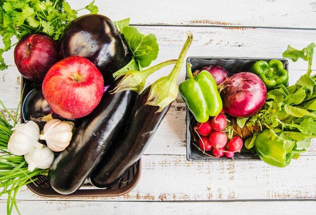 Fresh fruits; and vegetables in plastic basket over wooden table