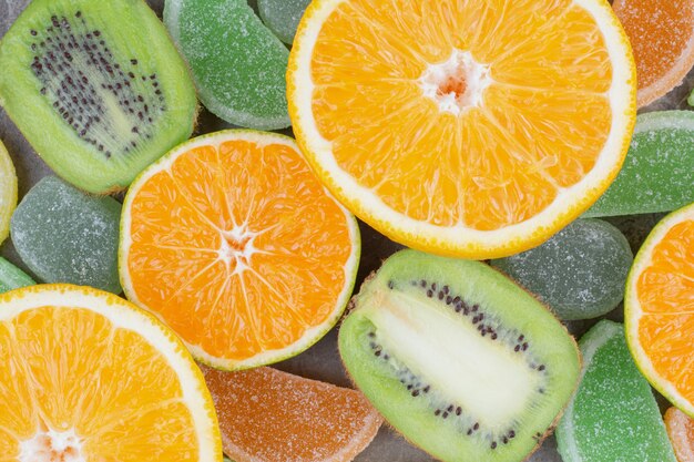 Fresh fruits with sweet marmalades on marble background.