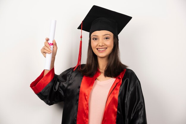 Свежий выпускник девушки с дипломом, позирует на белом фоне.