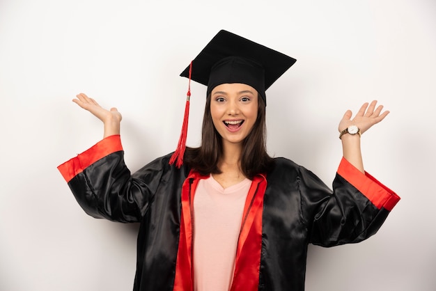 Fresh graduate in gown showing her hands on white background.