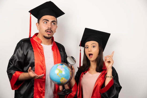 Fresh graduate students with globe looking joyful on white.