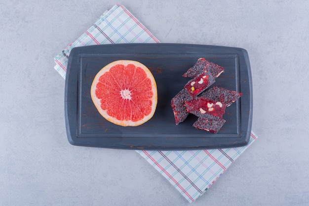 Fresh grapefruit slice and tasty oriental sweets on dark board.