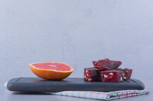 Fresh grapefruit slice and tasty oriental sweets on dark board.