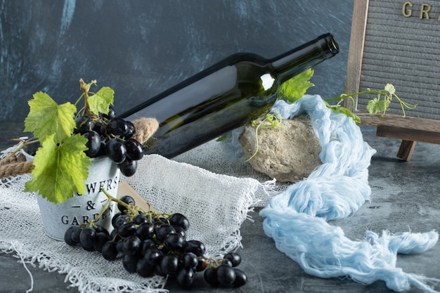 Fresh grapes in bucket with bottle of wine on sackcloth 