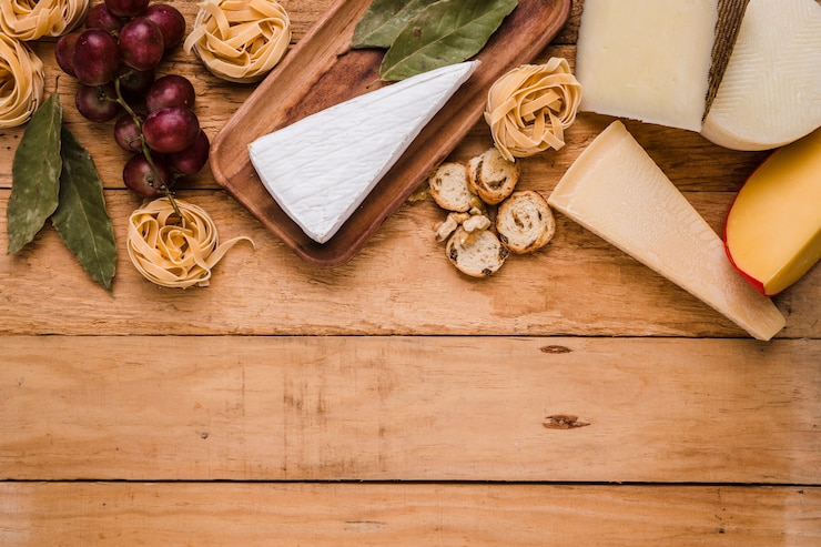 Free Photo fresh grapes; pasta; cheese and bay leaves on wooden counter