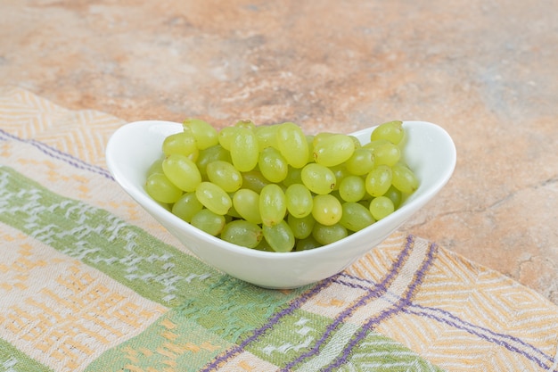 Fresh grapes in white bowl on tablecloth. High quality photo