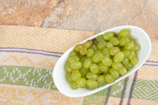 Fresh grapes in white bowl on tablecloth