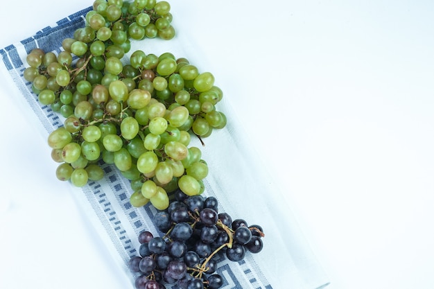 Free photo fresh grapes on white and kitchen towel background. flat lay.