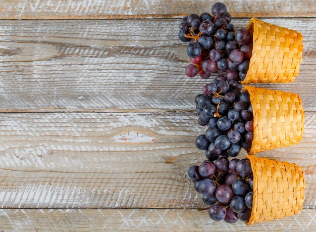 Fresh grapes in wicker baskets flat lay on a wooden background