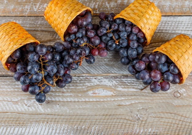Свежий виноград в плетеных корзинах на деревянном фоне. плоская планировка.