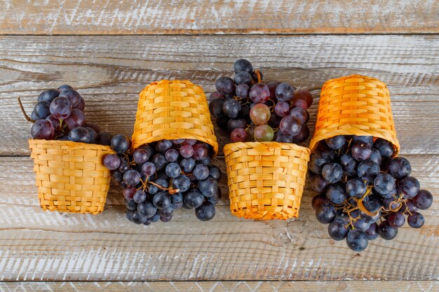 Free photo fresh grapes in wicker baskets on a wooden background. flat lay.