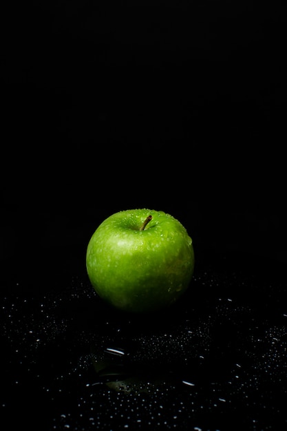 Свежее зеленое яблоко на черном