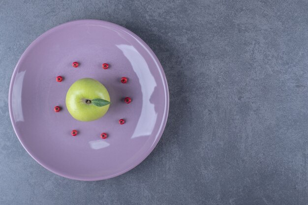 Fresh green apple on purple plate.