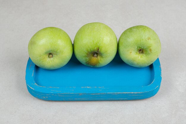 Fresh green apples on blue plate