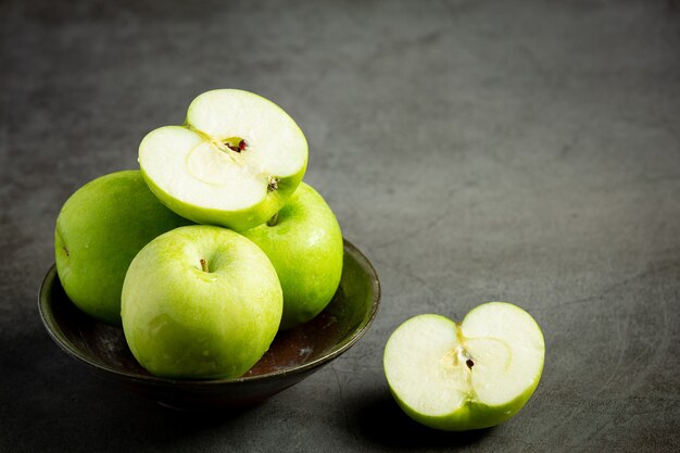Fresh green apples cut in half put in black bowl on dark background