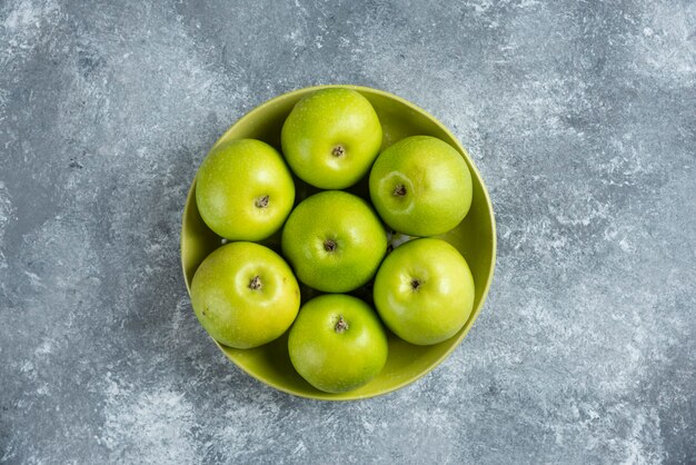 Fresh green apples on a green plate