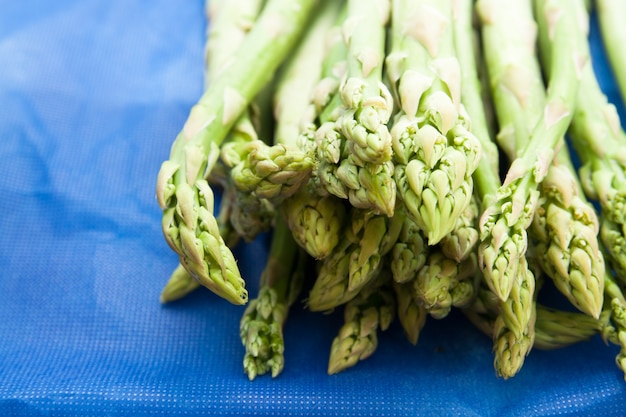 Foto gratuita suggerimenti verdi di asparagi freschi su sfondo blu
