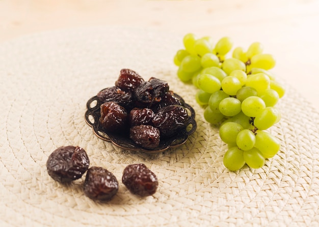 Fresh green grape near prunes on saucer