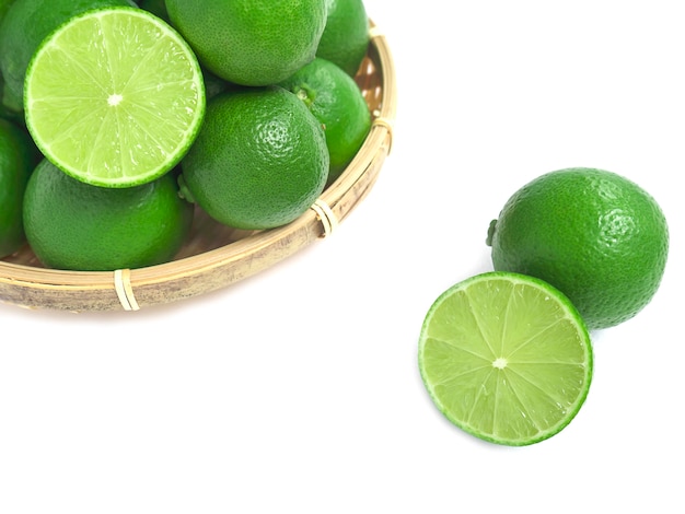 Free photo fresh green lime in the bamboo basket isolated on white background.