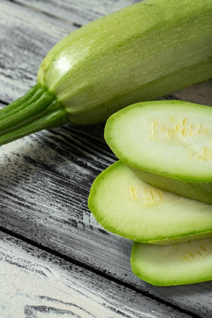 Free photo fresh green marrow sliced on grey wooden desk