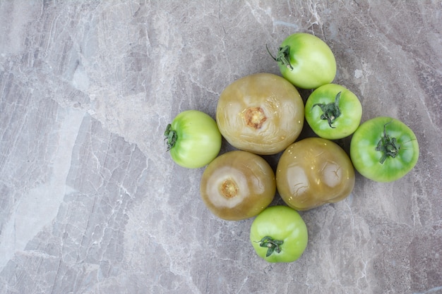 Бесплатное фото Свежие зеленые помидоры и маринованные помидоры на мраморной поверхности.