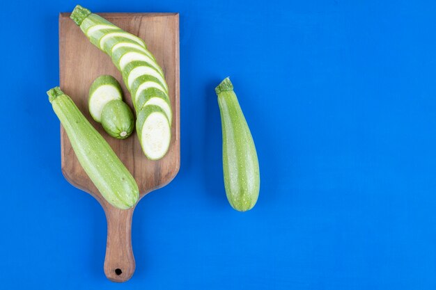 Fresh green zucchini and slices placed on wooden board. 