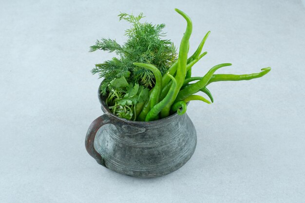 Fresh greens and chili peppers in classic mug.