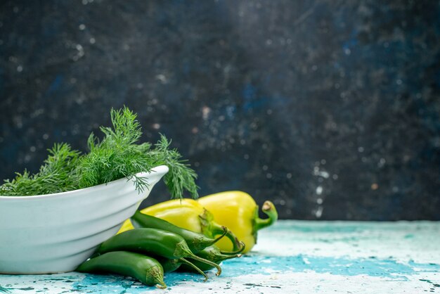 fresh greens inside plate with green bell-peppers and spicy peppers on bright-blue