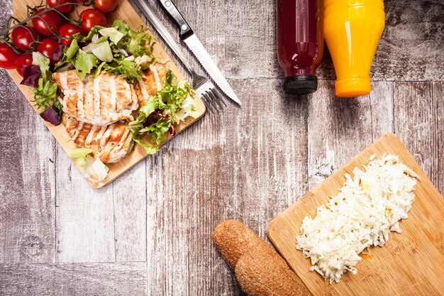 Fresh grilled chicken on wooden board next to healthy bread, tomatoes and salad. Healthy lifestyle and eating